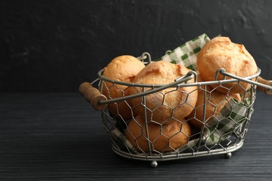 Metal basket with homemade tasty buns on black wooden table, closeup. Space for text