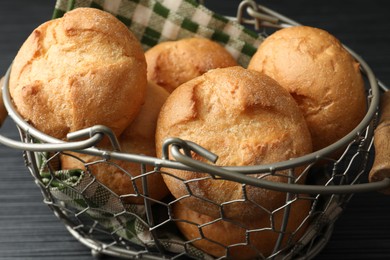 Photo of Metal basket with homemade tasty buns on black wooden table, closeup