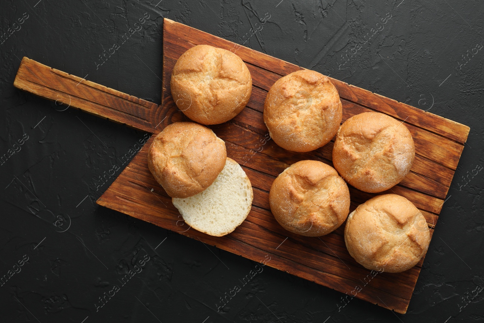 Photo of Homemade tasty buns on black textured table, top view