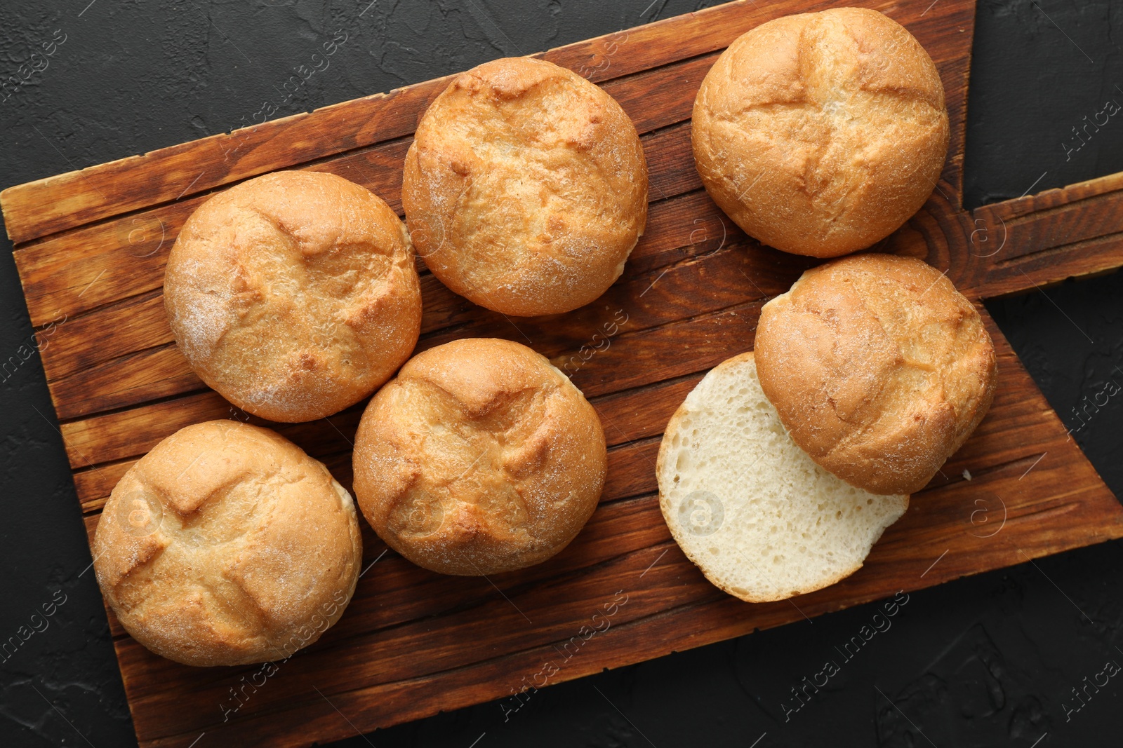 Photo of Homemade tasty buns on black textured table, top view