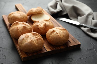 Board with homemade tasty buns on black textured table, closeup