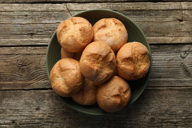 Photo of Homemade tasty buns in bowl on wooden table, top view