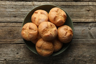 Photo of Homemade tasty buns in bowl on wooden table, top view