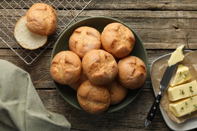 Photo of Homemade tasty buns, butter and knife on wooden table, flat lay