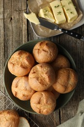 Photo of Homemade tasty buns, butter and knife on wooden table, flat lay