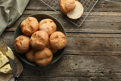 Photo of Homemade tasty buns, butter and knife on wooden table, flat lay. Space for text