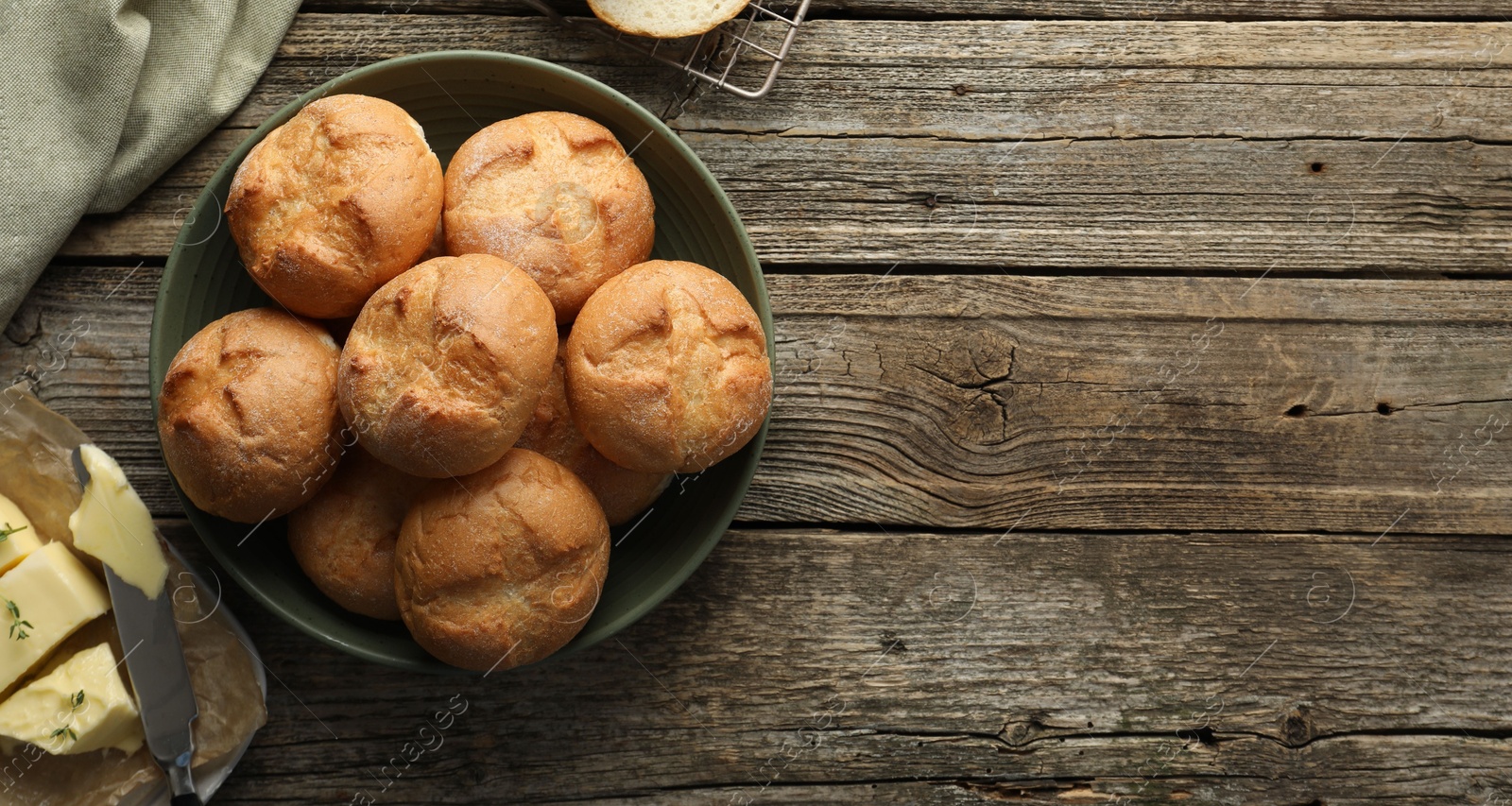 Photo of Homemade tasty buns, butter and knife on wooden table, flat lay. Space for text