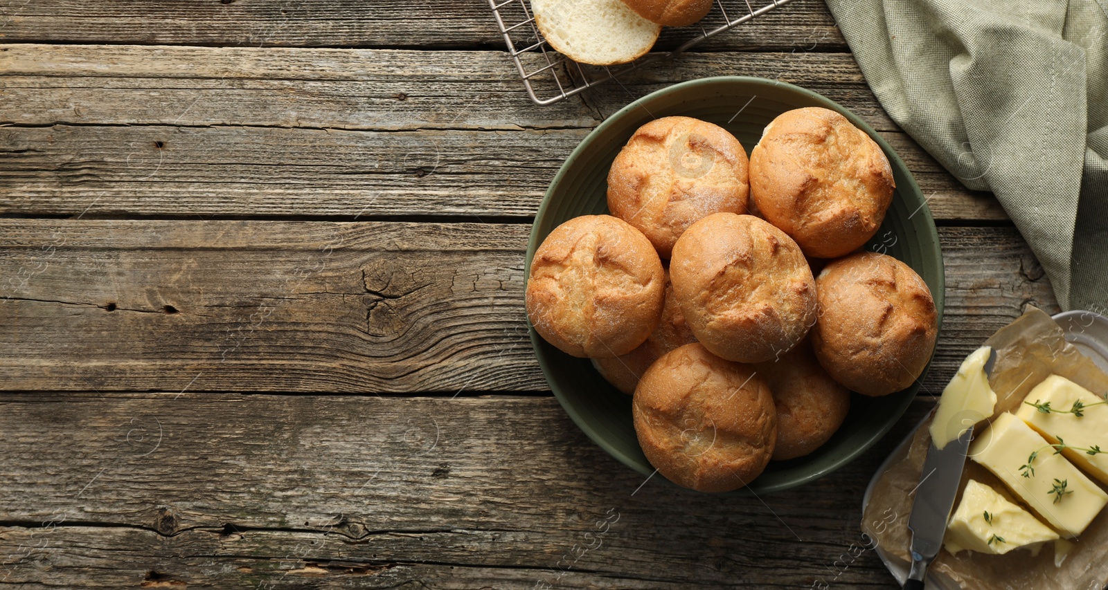 Photo of Homemade tasty buns, butter and knife on wooden table, flat lay. Space for text