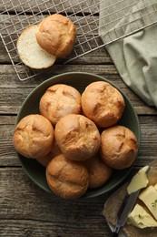 Photo of Homemade tasty buns, butter and knife on wooden table, flat lay