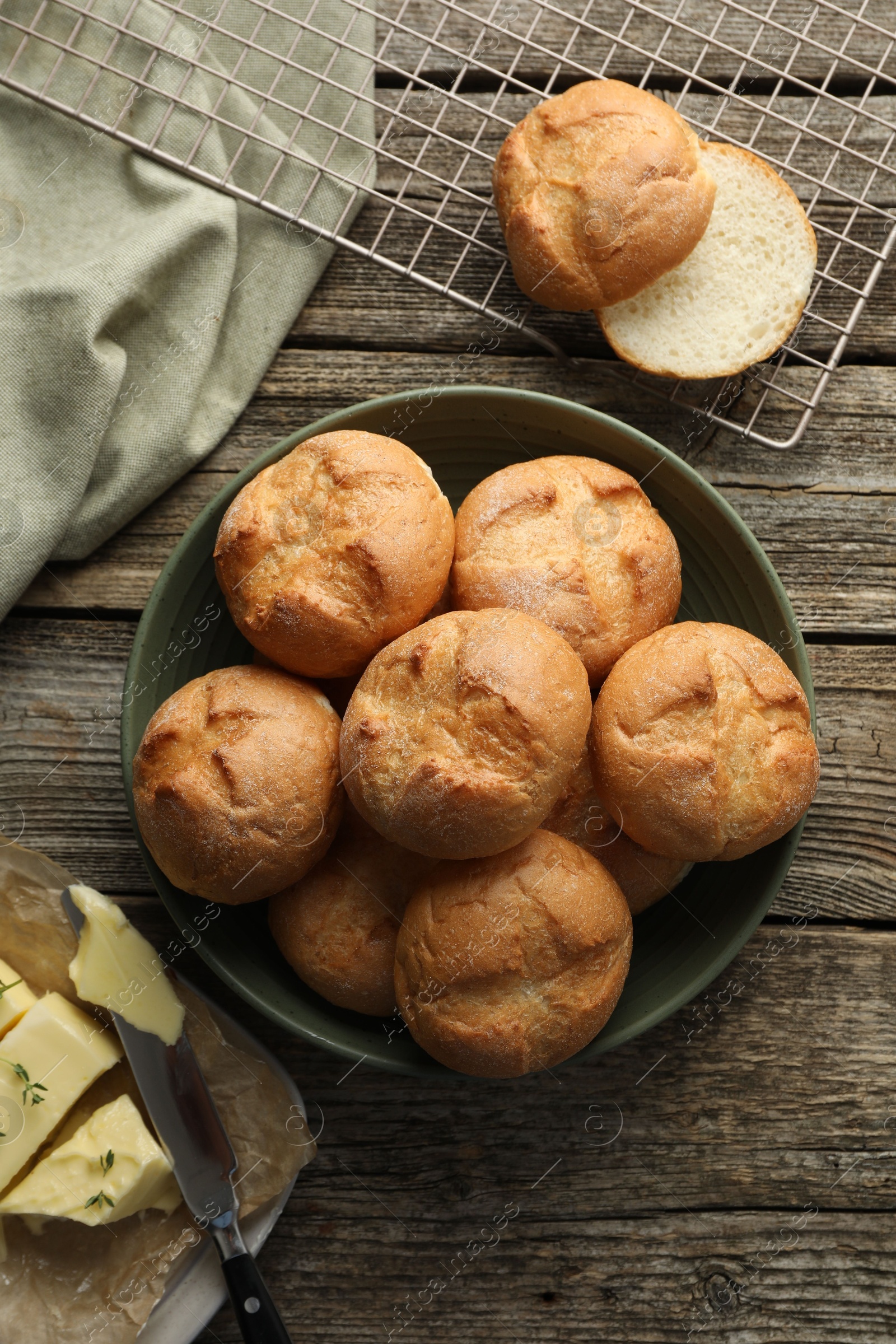 Photo of Homemade tasty buns, butter and knife on wooden table, flat lay