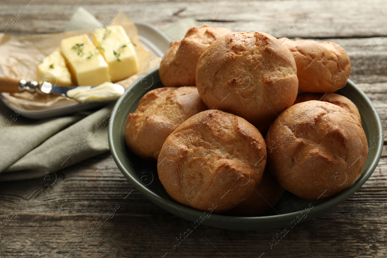 Photo of Homemade tasty buns in bowl on wooden table, closeup