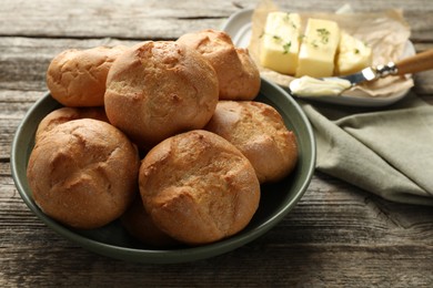 Photo of Homemade tasty buns in bowl on wooden table, closeup