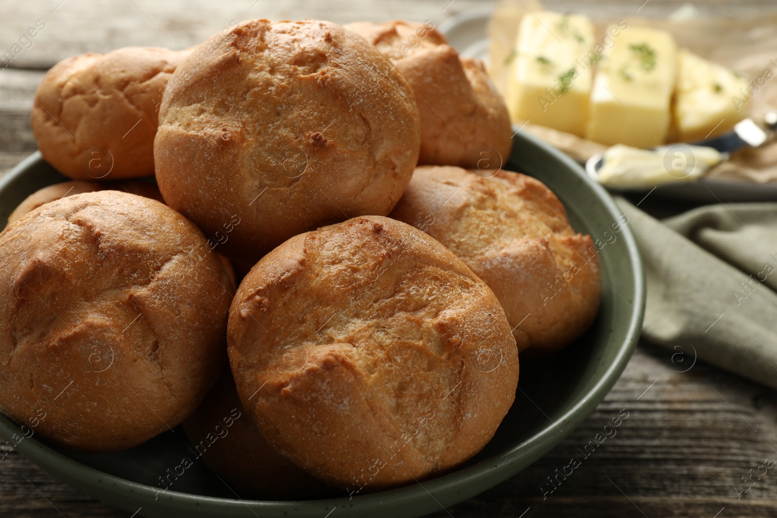 Photo of Homemade tasty buns in bowl on wooden table, closeup