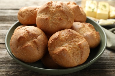 Homemade tasty buns in bowl on wooden table, closeup