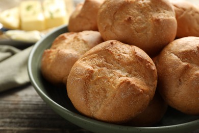 Photo of Homemade tasty buns in bowl on wooden table, closeup