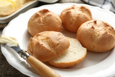 Photo of Plate with homemade tasty buns, butter and knife on table, closeup