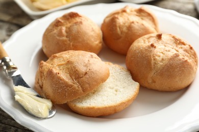 Photo of Plate with homemade tasty buns, butter and knife on table, closeup