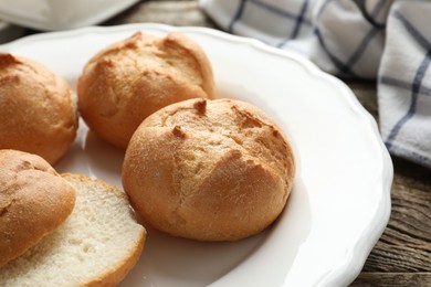 Photo of Plate with homemade tasty buns on wooden table, closeup