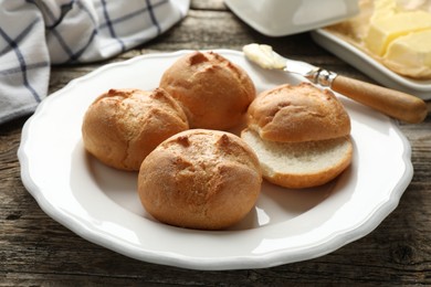 Photo of Plate with homemade tasty buns on wooden table, closeup