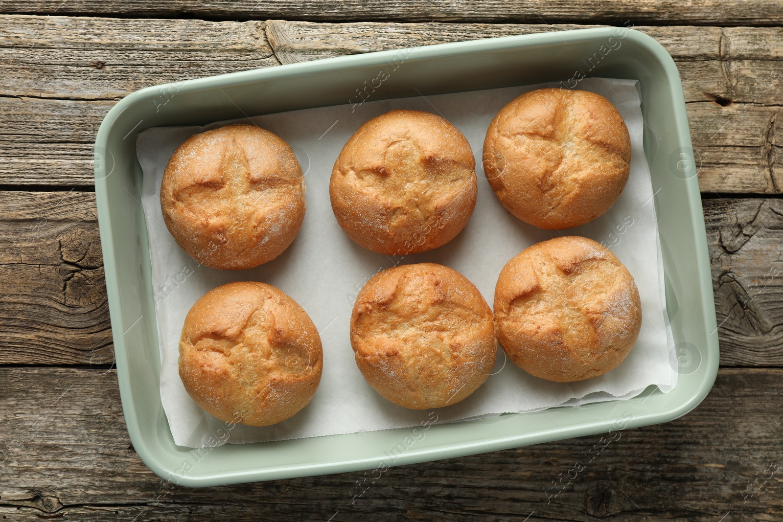 Photo of Homemade tasty buns in baking dish on wooden table, top view