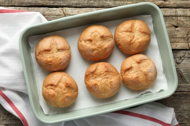 Photo of Homemade tasty buns in baking dish on wooden table, top view