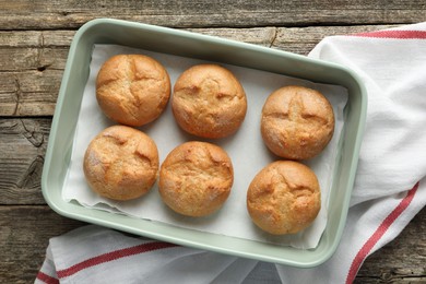 Photo of Homemade tasty buns in baking dish on wooden table, top view