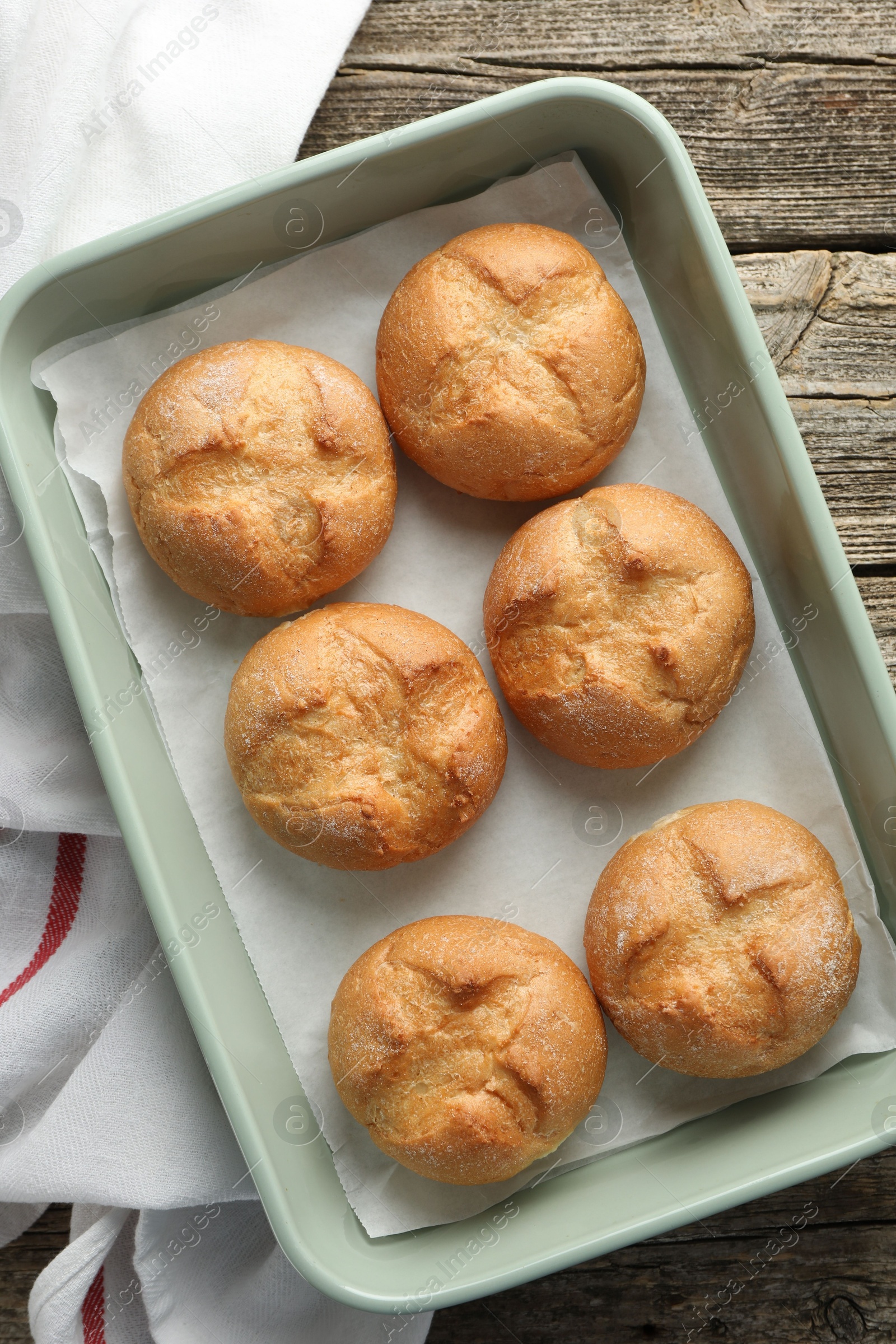 Photo of Homemade tasty buns in baking dish on wooden table, top view