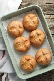 Photo of Homemade tasty buns in baking dish on wooden table, top view