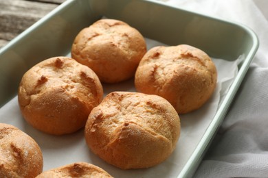 Photo of Homemade tasty buns in baking dish on table, closeup