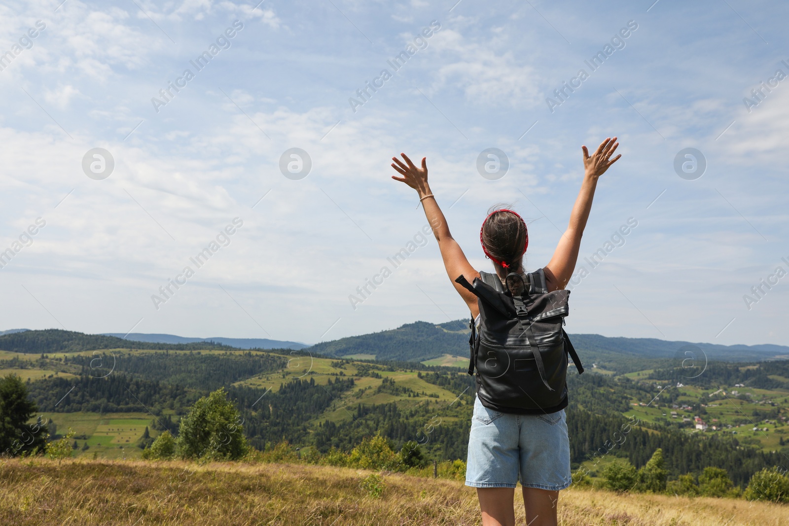 Photo of Tourist with backpack enjoying picturesque landscape with wide open arms, back view. Space for text