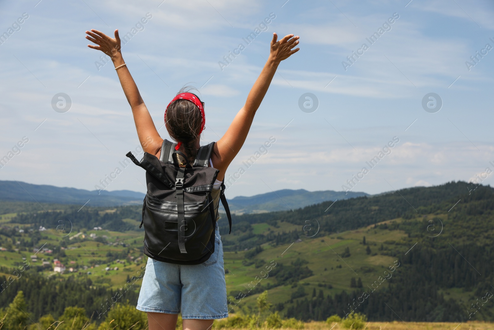 Photo of Tourist with backpack enjoying picturesque landscape with wide open arms, back view. Space for text