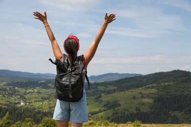 Tourist with backpack enjoying picturesque landscape with wide open arms, back view. Space for text