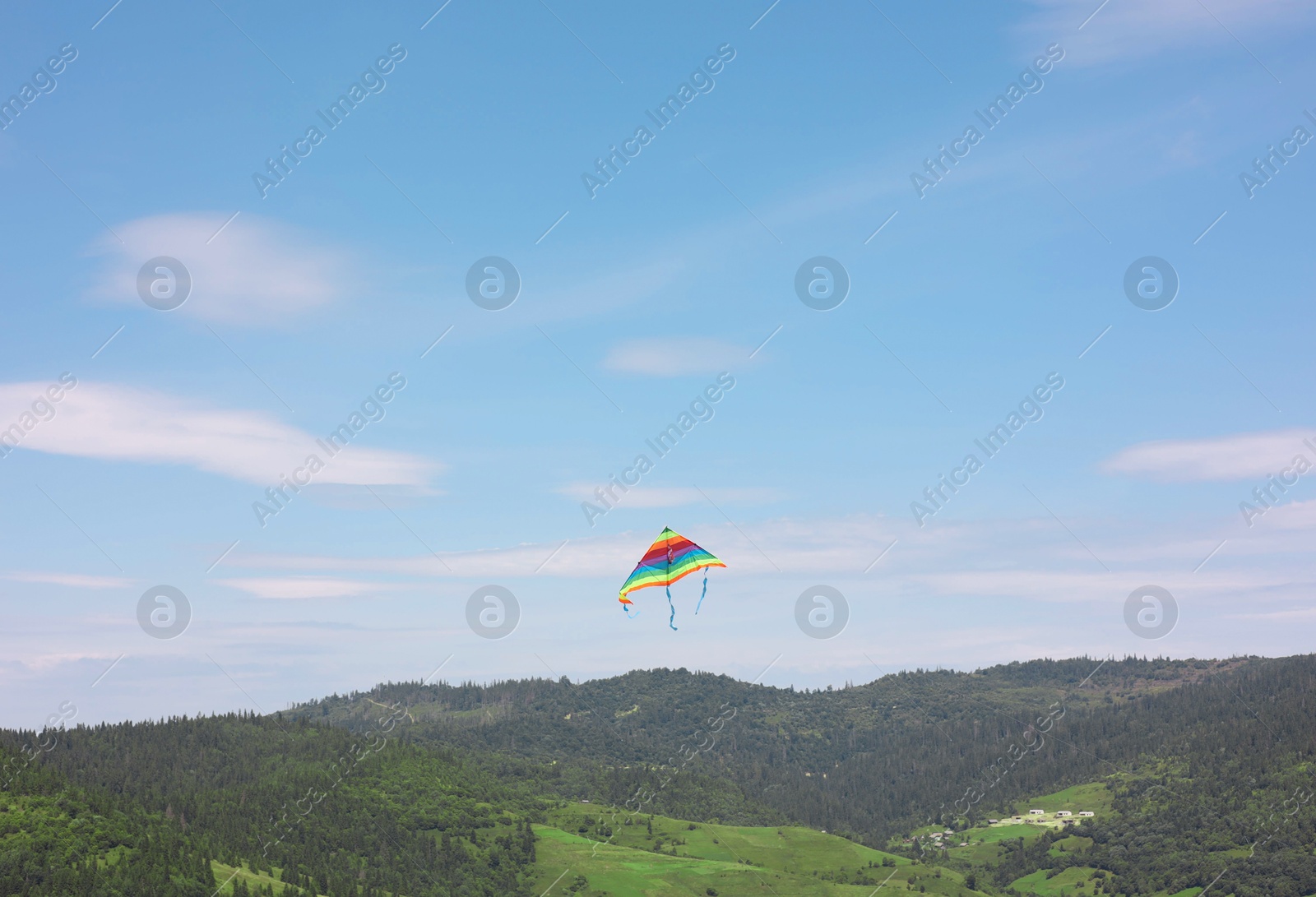 Photo of One colorful kite flying in mountains under blue sky