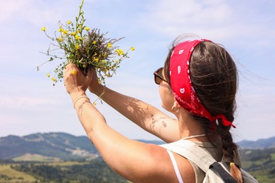 Woman holding bouquet of wild yellow flowers outdoors