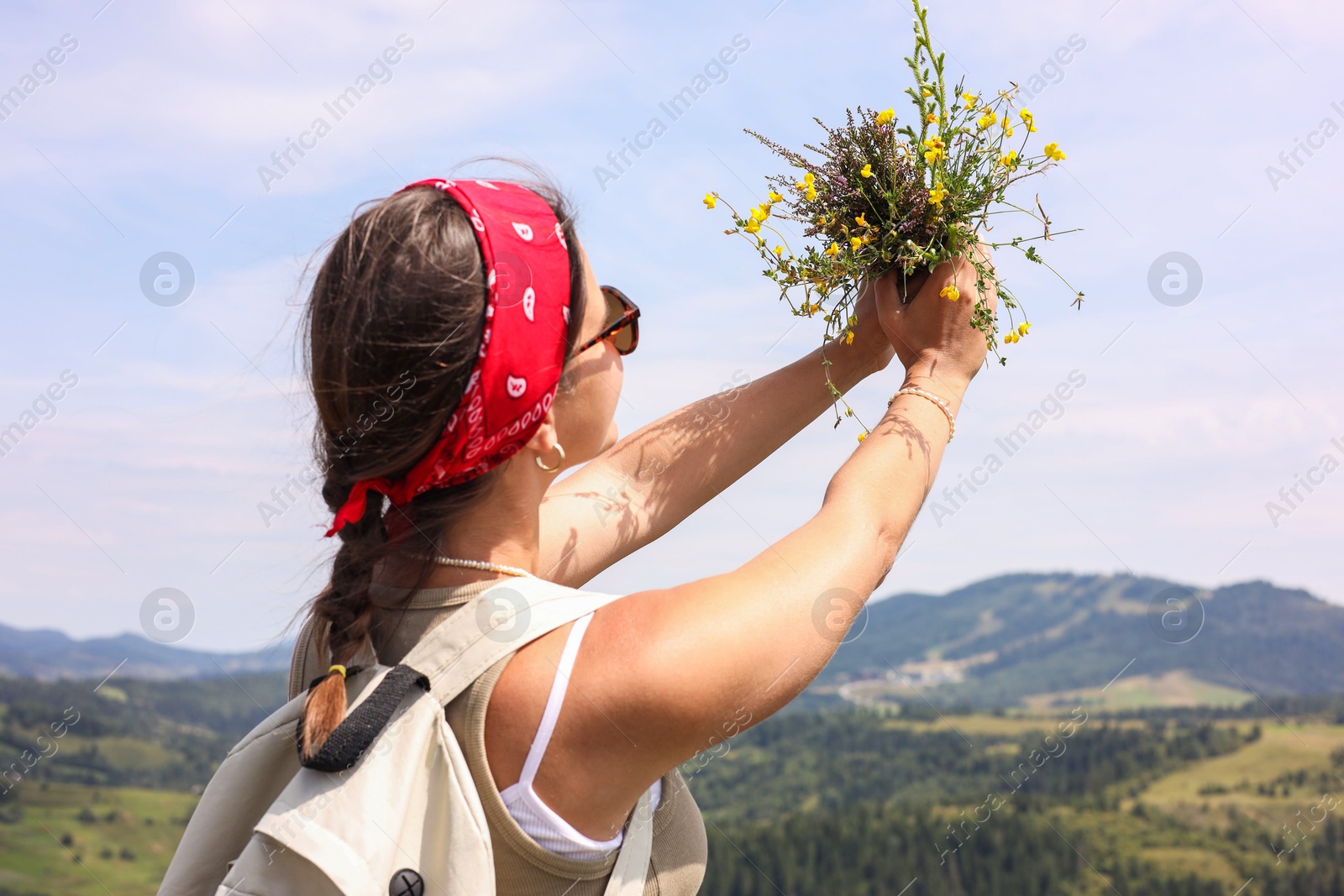 Photo of Woman holding bouquet of wild yellow flowers outdoors