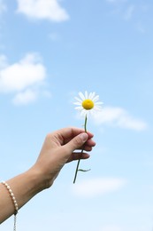 Photo of Woman holding beautiful chamomile flower outdoors, closeup