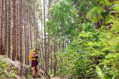 Photo of Young hiker with backpack in forest, space for text