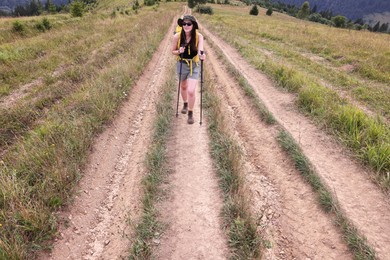 Photo of Young hiker with backpack and trekking poles in mountains