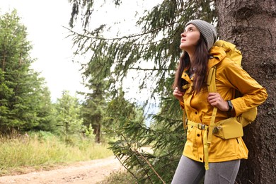 Photo of Young hiker with backpack in forest, space for text