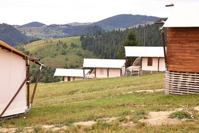 Photo of Green forest and many houses in mountains. Glamping site