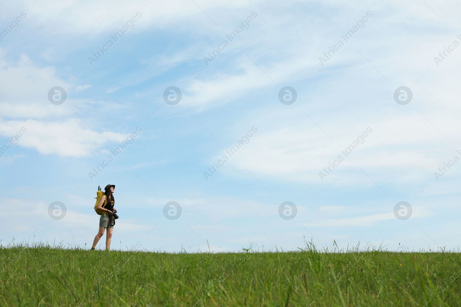 Photo of Young hiker with backpack and camera in field, space for text