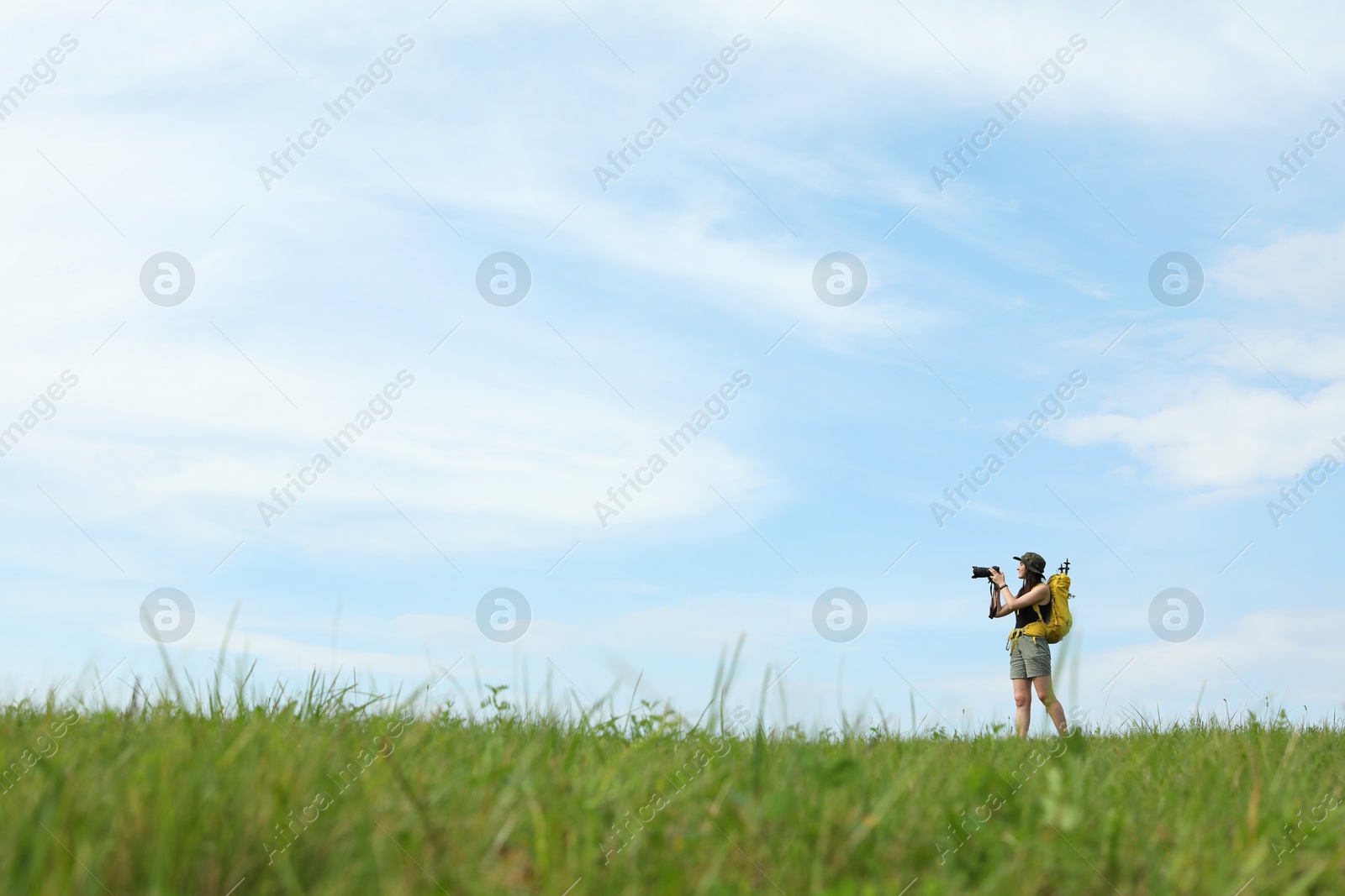 Photo of Young hiker with backpack and camera in field, space for text