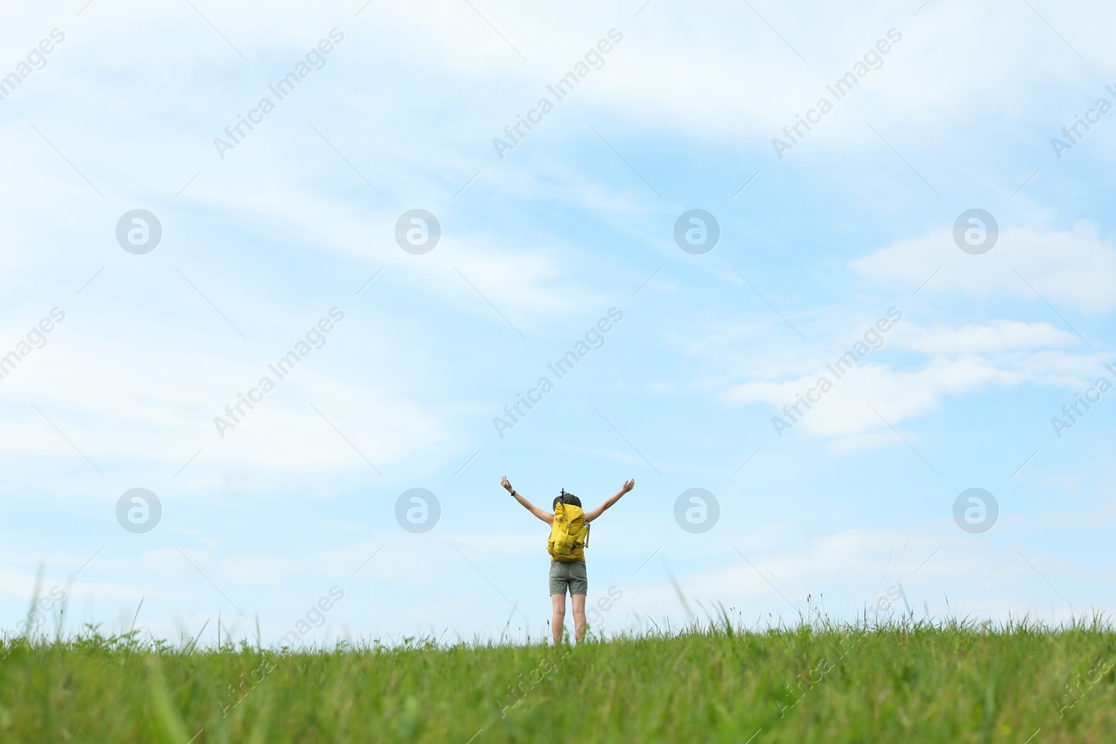 Photo of Young hiker with backpack in field, back view. Space for text