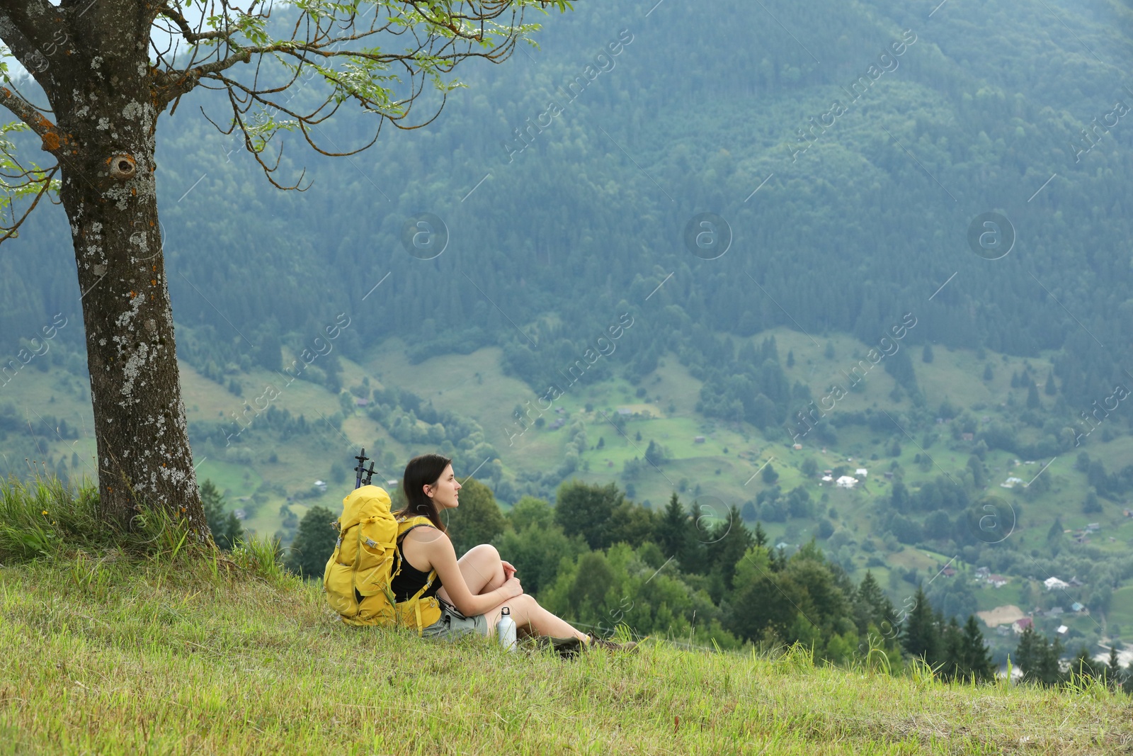 Photo of Young hiker with backpack in mountains, space for text