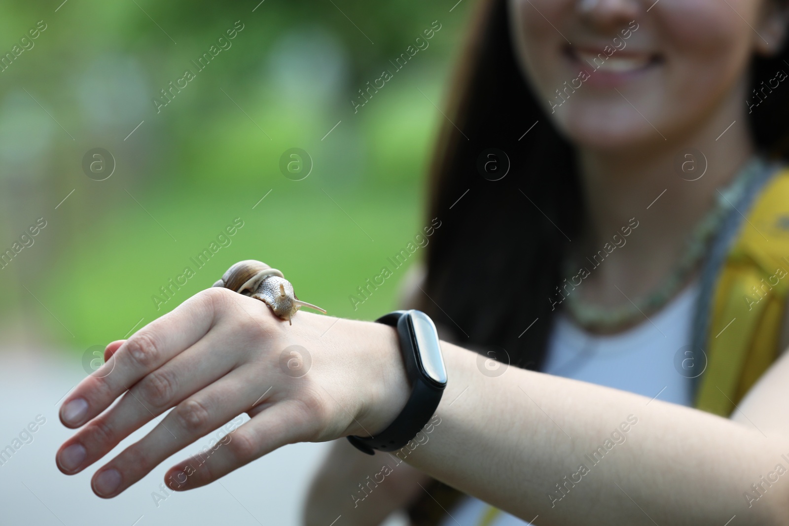 Photo of Woman with cute little snail outdoors, closeup