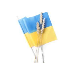 Photo of Ears of wheat and Ukrainian national flag isolated on white, top view