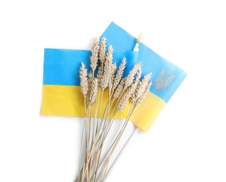 Ears of wheat and Ukrainian national flag isolated on white, top view