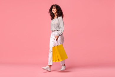 Smiling woman with shopping bags on pink background