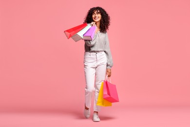 Photo of Smiling woman with colorful shopping bags on pink background