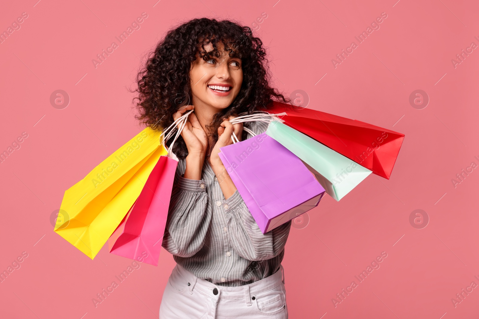 Photo of Smiling woman with colorful shopping bags on pink background